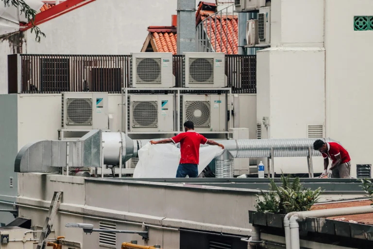 Techniciens devant des groupes de climatisation en toiture